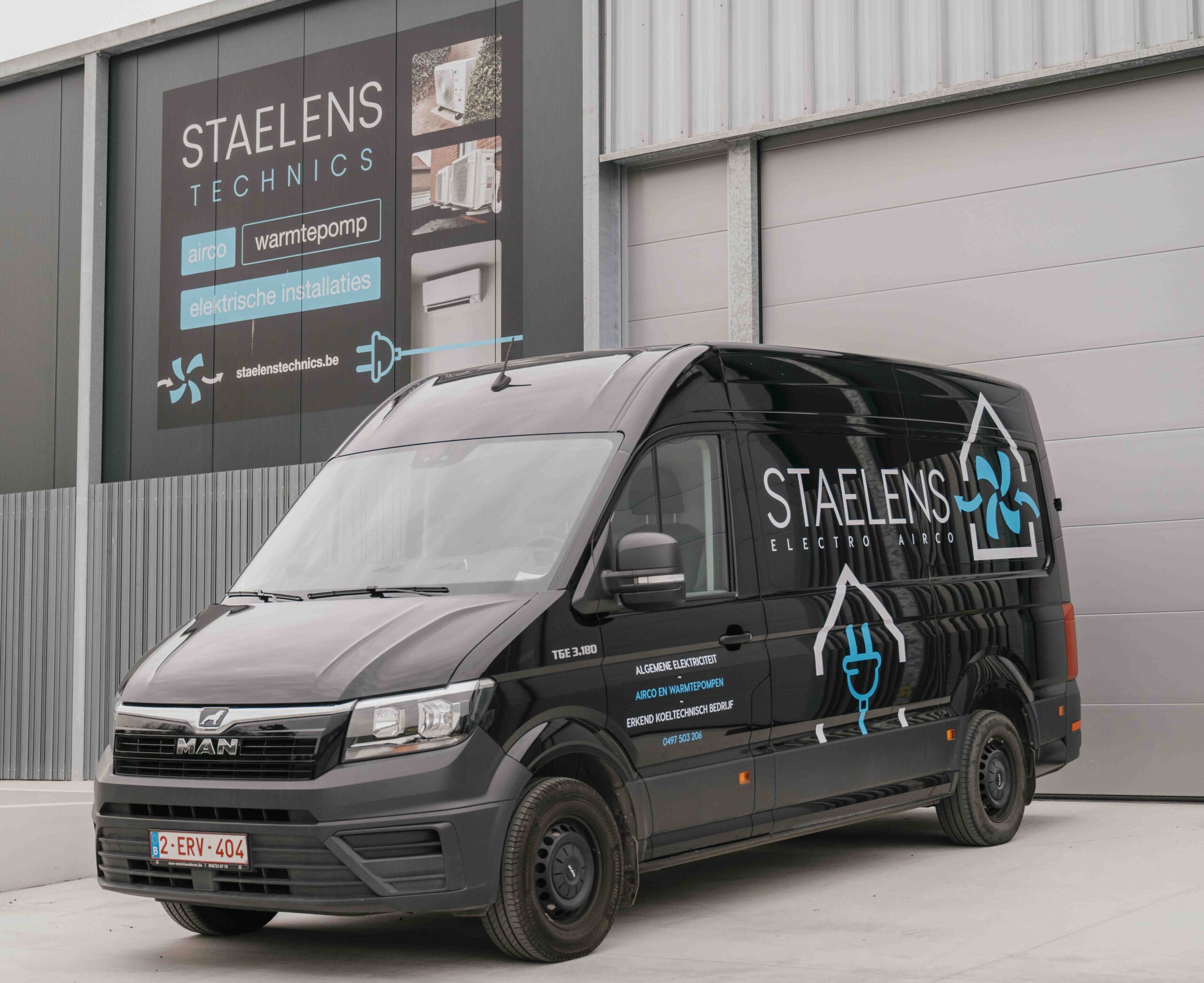 Black STAELENS van with ELECTRO and AIRCO branding parked in front of a gray industrial building with a large sign promoting electrical installations.
